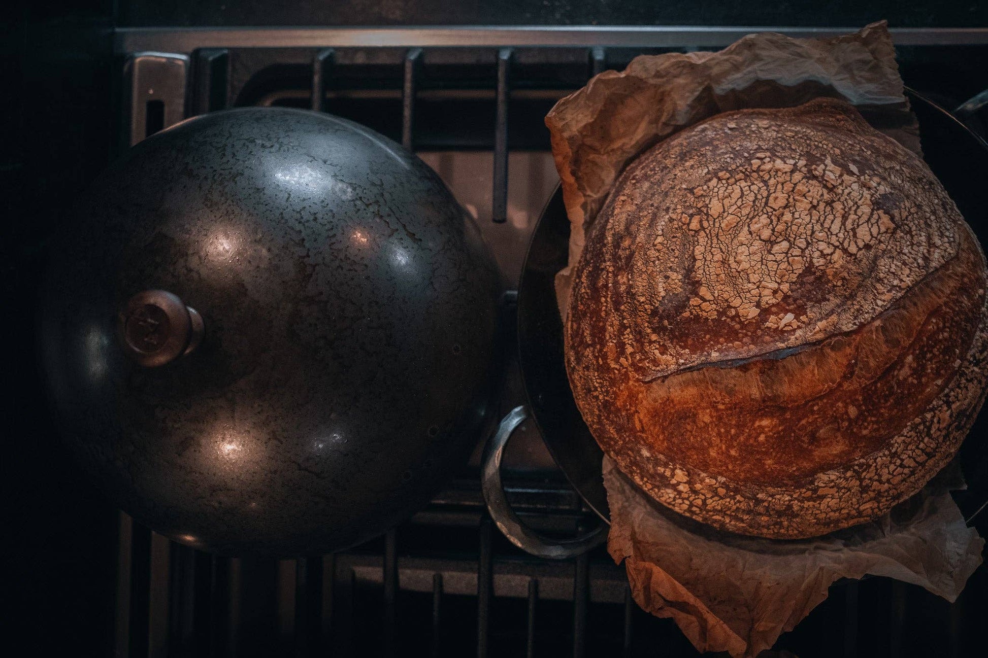 Domed carbon steel bread cloche cover and rustic sourdough boules in Dutch oven.