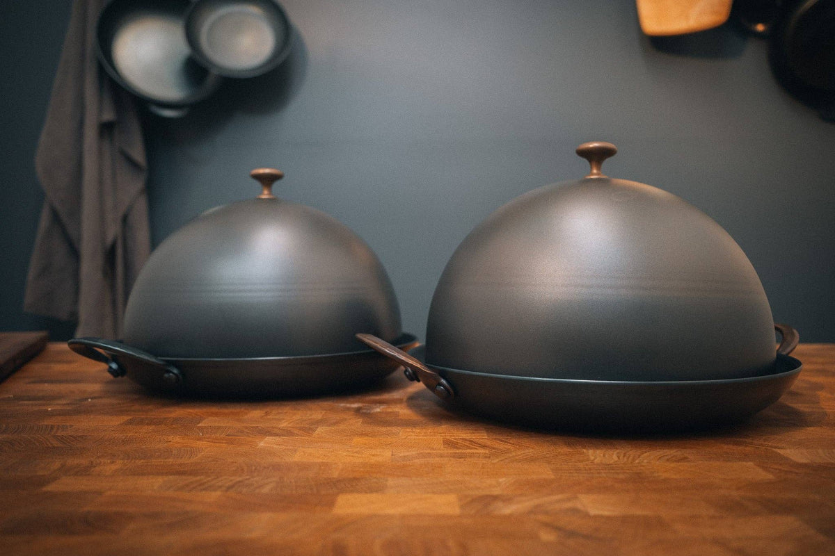 Bread Cloche domes for 11 inch roaster, spun 14 gauge carbon steel with copper knobs, creating rustic loaf heat retention inside.