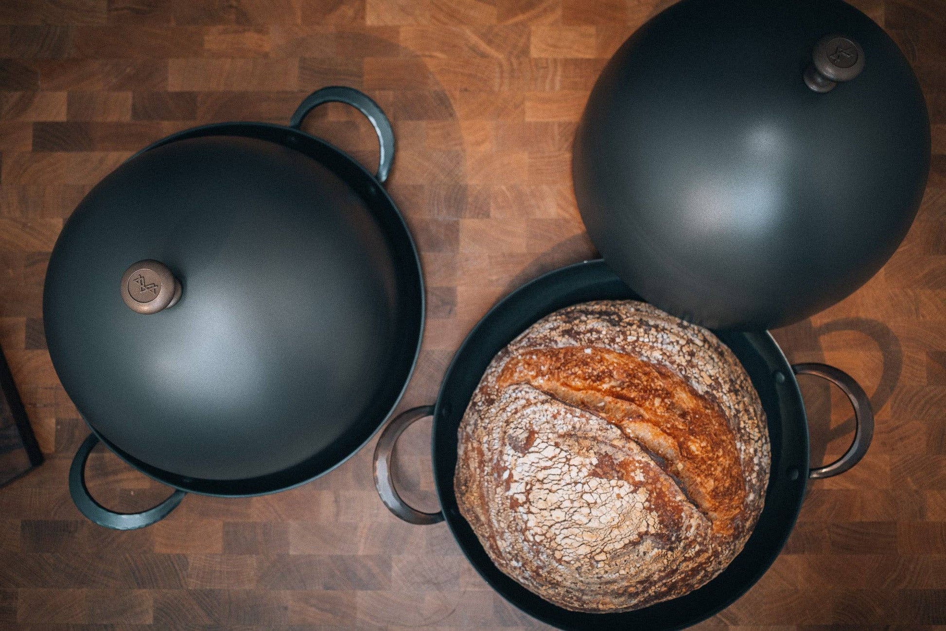 Bread Cloche and 11" roaster with rustic boule on wooden surface.