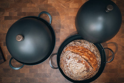 Bread Cloche and 11" roaster with rustic boule on wooden surface.